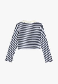 Navy ja valge triibuline pika varrukaga lühike topp, millel on kreemjas krae, pehme tekstuuri ja fitted disain.