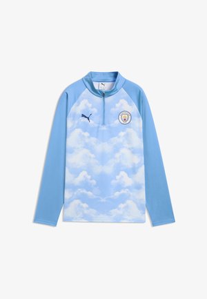Hellblaues langärmliges Sportoberteil mit Wolkenmuster, schwarzes Puma-Logo auf der rechten Brust und das Manchester City Fußballklub-Wappen auf der linken Brust.