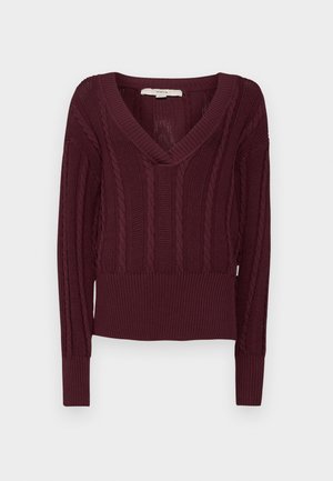 Pulover burgund cu model texturat, cu guler în V, mâneci lungi și tiv dantelat. Confectionat dintr-un material moale și elastic.