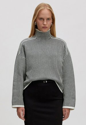Zwart-witte gestreepte coltrui met een losse pasvorm, verlaagde schouders en ribbelstructuur. Ggedragen over een zwarte rok.