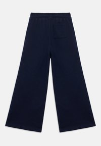 Tengerészkék, bő szárú melegítőnadrág elasztikus derékpánttal és hátsó zsebfedővel. Puha, texturált anyagból készült.