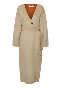 Beige lange wollen jas met V-hals, enkele donkere knoop, brede riem en oranje voering die zichtbaar is aan de binnenkant van de kraag.