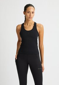 Zwarte sportieve tanktop van rekbare stof met een ronde halslijn en brede bandjes, gecombineerd met zwarte leggings met een logo.