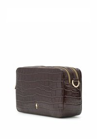 Prostokątna torba na ramię w ciemnobrązowym kolorze, z fakturą skóry krokodyla, złotym zamkiem błyskawicznym i małym złotym logo na przedniej stronie na białym tle.