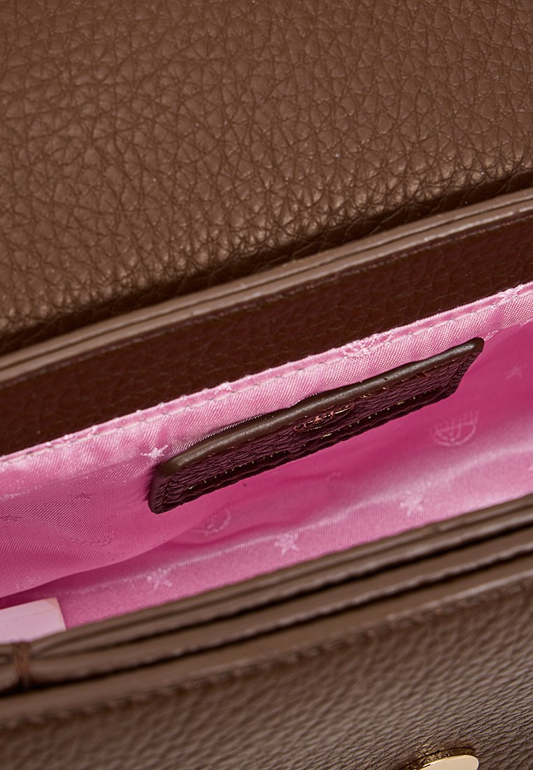 Bolso de cuero marrón con textura de guijarro, forrado en el interior con tela rosa y con una pequeña etiqueta de cuero negro en su interior.