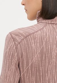 Heled roosa jakk, millel on tekstuuriga vertikaalsed triibud, kõrge krae ja nähtavad õmblused seljal. Pehme, kergelt veniv materjal.