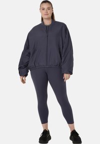 Navyblaue Bomberjacke mit Reißverschluss und elastischem Saum, kombiniert mit passenden Leggings. Glattes, leichtes Material, lässige Passform.