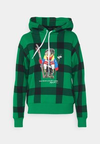 Zeleno-černá kostkovaná mikina s kapucí a stahovací šňůrkou, uprostřed s grafikou medvěda v lyžařském oblečení. Materiál s příměsí bavlny.
