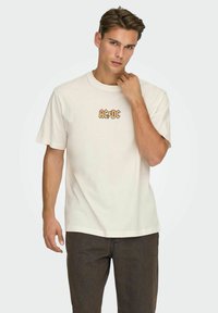 Cream cotton t-shirt featuring an orange AC/DC logo on the chest, round neck, short sleeves, and a relaxed fit with straight cut.