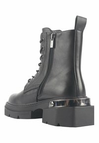 Crne kožne gležnjače s bočnim zatvaračem, vezanjem sprijeda, debelim đonom i metalnim detaljem na peti s "NINE WEST" brandom.