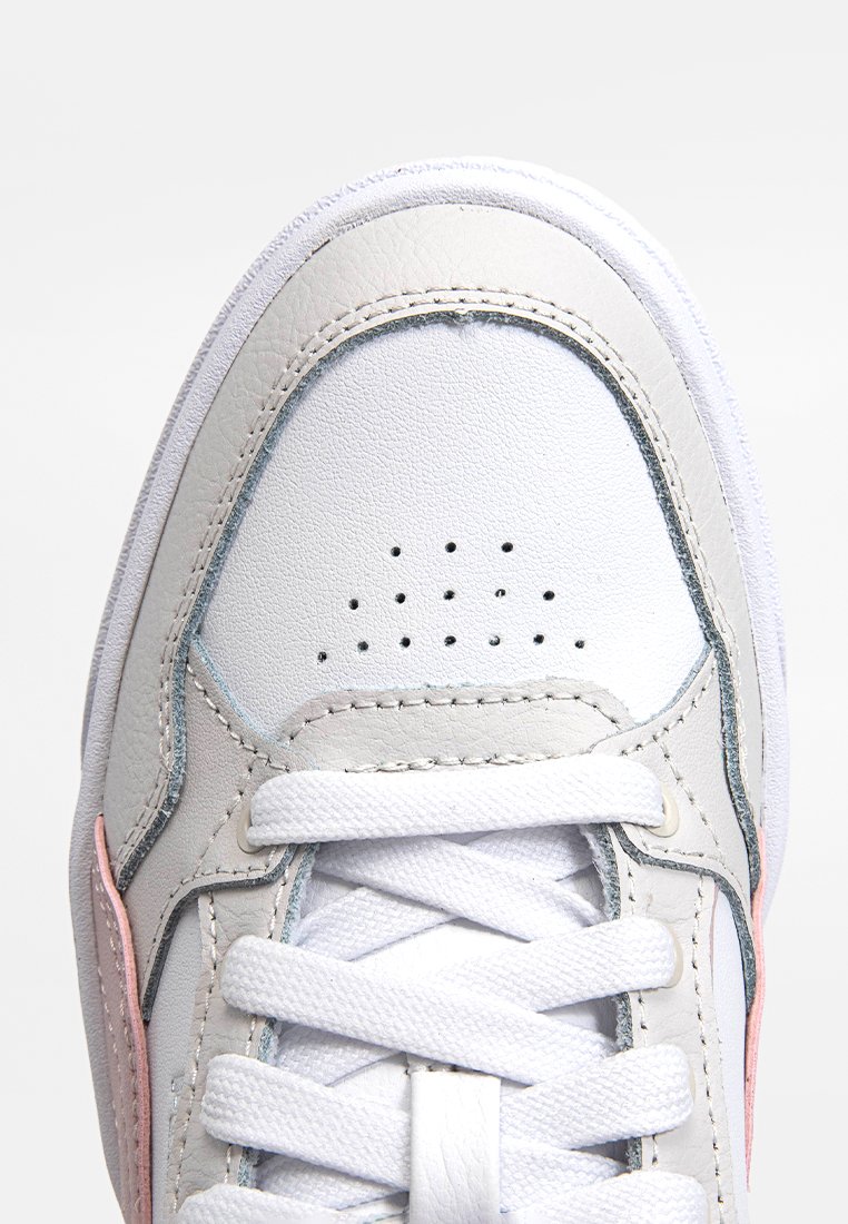 Sneaker in pelle bianca con una texture liscia, caratterizzata da accenti rosa e blu, sezione anteriore forata e lacci bianchi.
