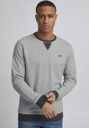 Light gray sweatshirt with dark gray accents, crew neckline, ribbed cuffs and hem, featuring a small logo on the chest. Smooth texture.