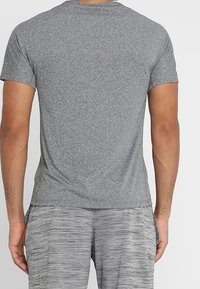 Šedé tričko s krátkým rukávem vyrobené z jemné, strukturované látky s kulatým výstřihem a přiléhavým střihem. Zadní pohled ukazuje hladké švy.