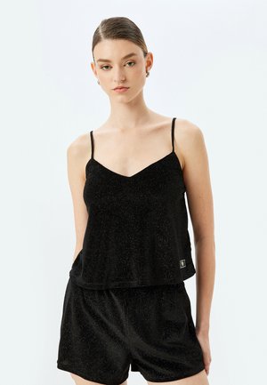 Camisole noire avec des fines bretelles, présentant un décolleté en V et une coupe décontractée, associée à un short assorti, le tout en tissu doux et scintillant.