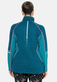 Türkisfarbene Sportjacke mit hohem Kragen, pinken Akzenten und reflektierenden Details. Verfügt über einen strukturierten Stoff und ein aerodynamisches Design.