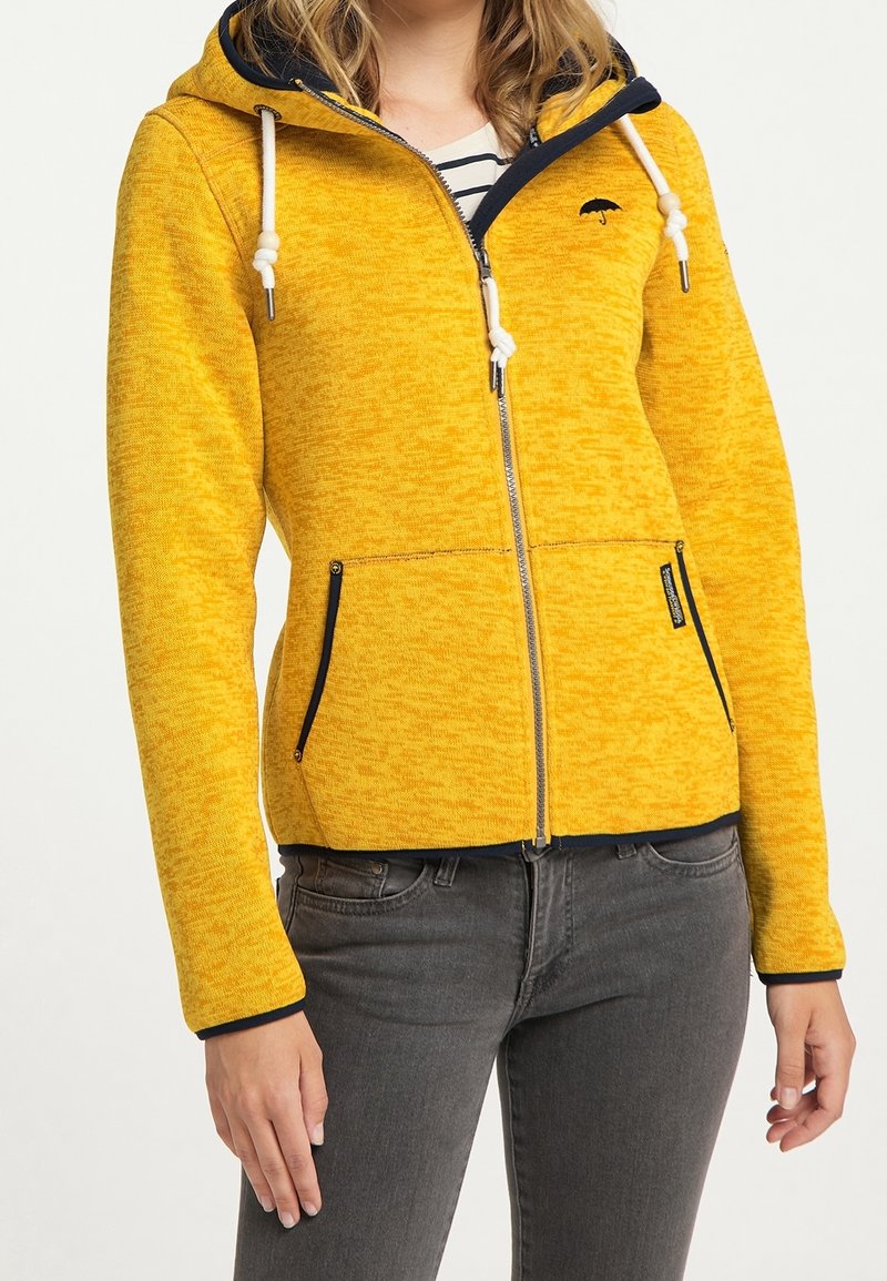 Sweat à capuche jaune texturé avec fermeture éclair, accents bleu marine, capuche avec cordons de serrage, et deux poches zippées à l'avant.