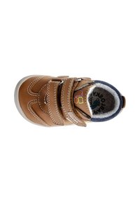 Zapato de cuero marrón con punta redondeada, dos correas de Velcro, costuras blancas y forro de paño gris. Presenta un logo colorido en el interior.
