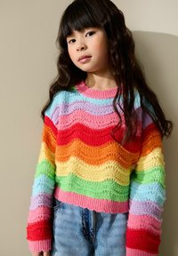 Pull tricoté présentant des rayures ondulées aux couleurs de l'arc-en-ciel : rouge, orange, jaune, vert, bleu et violet. Design court avec bords côtelés.