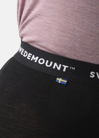 Svart elastisk midjeband med "SWEDEMOUNT™" i vit text och en liten svensk flagga som accent, i kombination med en lila topp.