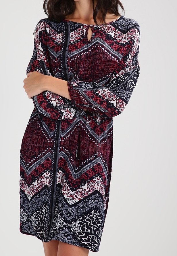 Rotes und marineblau gemustertes Kleid mit langen Ärmeln, das über einen Schlüsselloch-Ausschnitt, ein Zickzackdesign und detaillierte Blumenakzente verfügt. Weicher Stoff.
