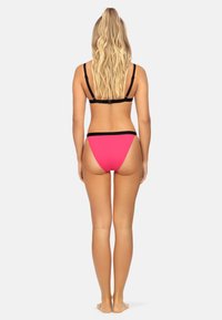 Zestaw bikini z czarnym topem na ramiączkach i różowymi majtkami, o dopasowanym fasonie. Materiał wydaje się gładki, podkreślając minimalistyczny styl.