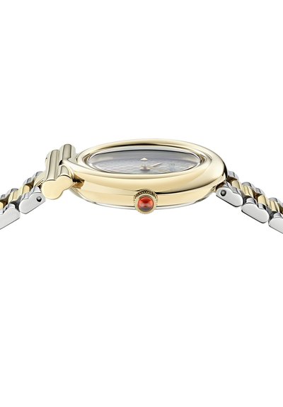 Reloj de pulsera de oro y plata visto de lado, mostrando una caja redondeada con una corona de gema roja y una pulsera de metal articulada.