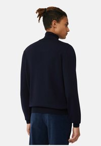 Maglione navy in morbido punto con collo alto, polsini e orlo a coste. Presenta un design della schiena senza cuciture. Adatto per essere indossato a strati.
