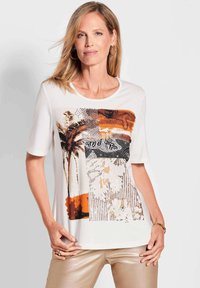 Korte mouw witte T-shirt met een kleurrijke grafische print in aardetinten, waaronder oranje en zwart, en gestructureerde patronen.