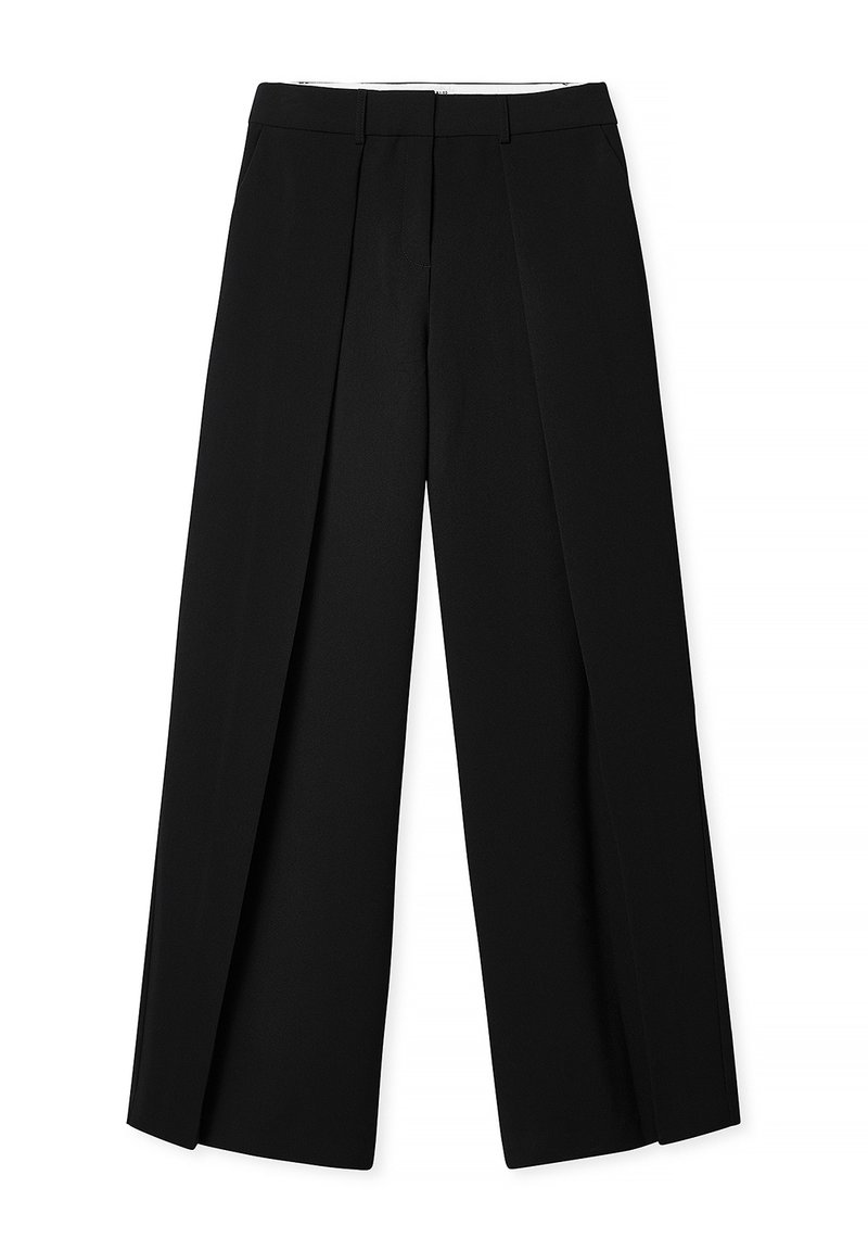 Pantalones negros de corte ajustado con pata ancha, que presentan pliegues frontales y una textura suave. Tienen una cintura ajustada y sin herrajes visibles.