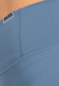 Leggings blu a vita alta con una texture liscia, caratterizzati da dettagli di cucitura visibili e un piccolo marchio nero in vita.