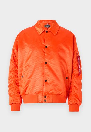 Giacca bomber in raso arancione brillante con bottoni neri, polsini a coste e tasche laterali. Presenta un motivo sottile e un'etichetta con il marchio sulla manica.