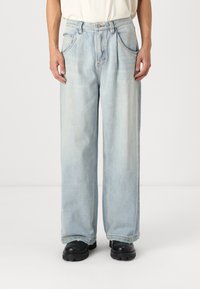Jeans en denim bleu clair, à jambes larges, avec deux poches avant et un léger délavage. Finition avec une fermeture à bouton et des détails de couture subtils.
