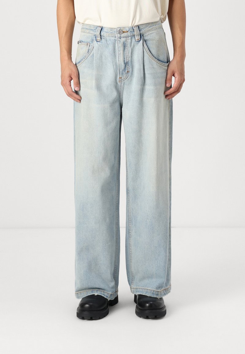 Jeans en denim bleu clair, à jambes larges, avec deux poches avant et un léger délavage. Finition avec une fermeture à bouton et des détails de couture subtils.