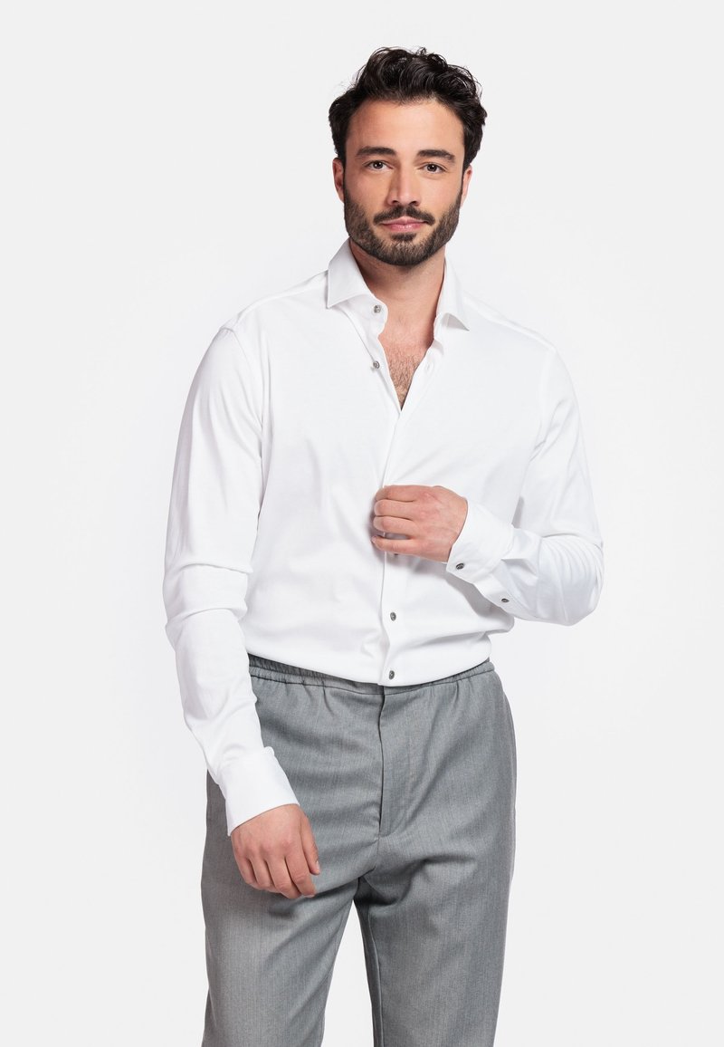Witte lange mouwen shirt van een katoenmix, met een spread collar en knoopsluiting. Gecombineerd met grijze broeken met elastische taille.