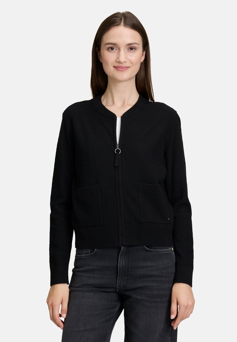 Zwarte zip-up cardigan van textuurstof, met een ronde halslijn, twee voorzakken en lange mouwen.