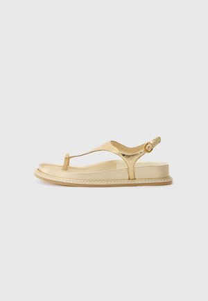 Guldmetallic tanga-sandaler med flad sål, ankelrem og simpel spænde-detajle. Glat overflade og minimalistisk design.