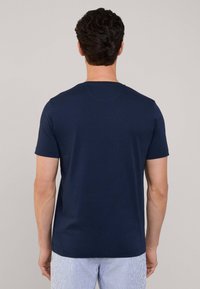 T-shirt en coton bleu marine avec un col rond et des manches courtes, mettant en avant une texture lisse et un design simple. Aucuns motifs visibles.