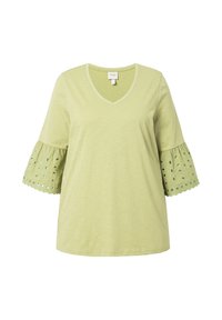 T-shirt verde chiaro con scollatura a V e maniche a ruffles. Le maniche presentano fori a occhio e un bordo scallop. Tessuto morbido e leggero.