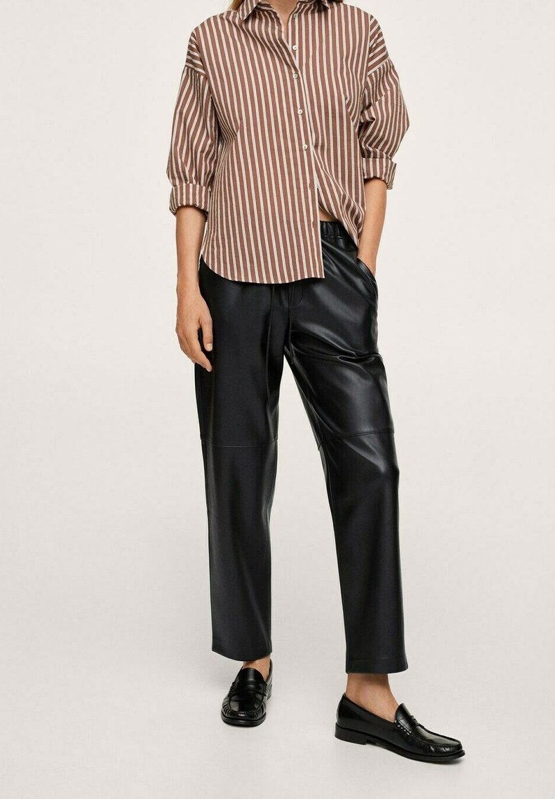 Chemise boutonnée à rayures marron et blanches, coupe ample. Pantalons en simili cuir noir, coupe droite. Mocassins noirs. Design simple, sans motifs.