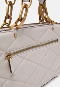 Borsa a tracolla trapuntata grigia chiara con catene dorate, dotata di tasca frontale con zip e finitura opaca, che mette in risalto dettagli a forma di diamante.