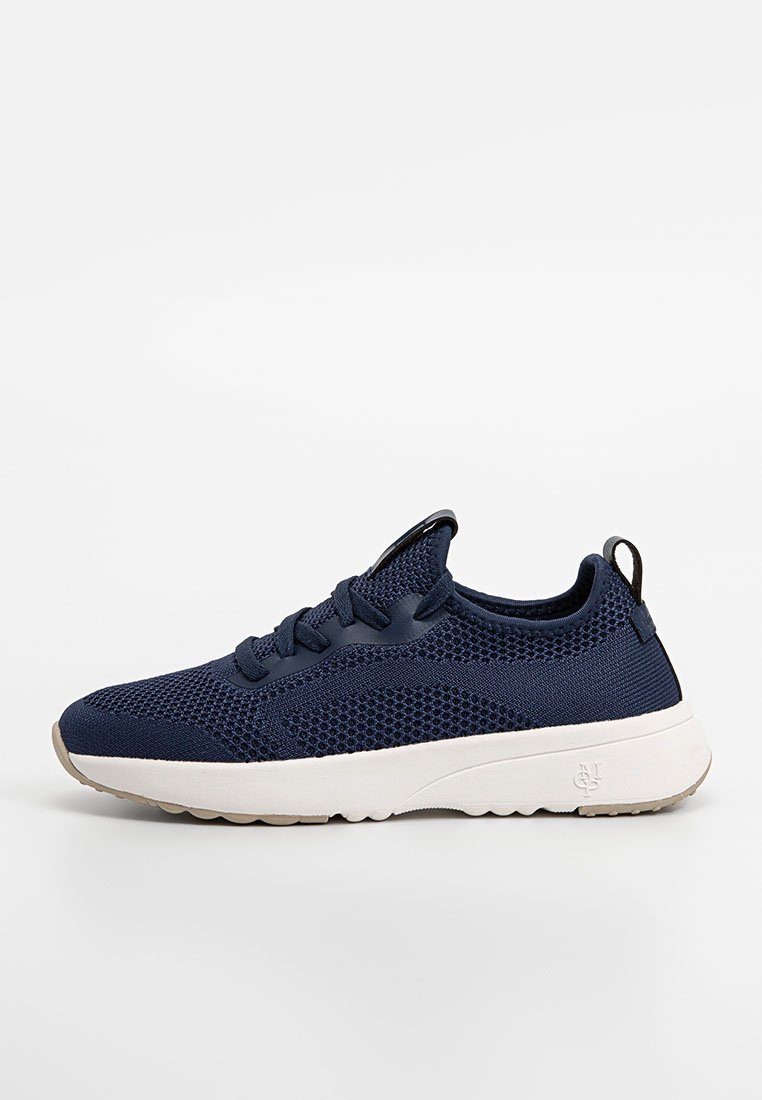 Granatowe sneakersy z siateczki z teksturowaną cholewką, okrągłym noskiem, sznurowanym zapięciem oraz białą podeszwą środkową. Wyposażone w pętelkę przy pięcie ułatwiającą zakładanie.