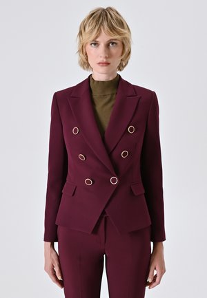 Burgunderfarbener doppelreihiger Blazer mit goldenen runden Beschlägen, mit Revers und zwei Fronttaschen. Glatte Stoffoberfläche.
