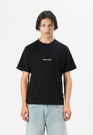 Black cotton t-shirt with a crew neckline and short sleeves. Features white cursive text on the chest. Paired with light blue denim shorts.