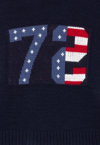 Maglione lavorato a maglia blu navy con un grande motivo "72" in blu, rosso e bianco con motivo di stelle e strisce sui numeri.
