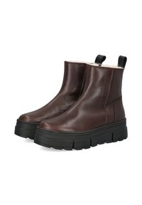 Braune Leder-Stiefeletten mit strukturierter Oberfläche, ausgestattet mit einer dicken schwarzen Sohle und Zuglaschen für ein einfaches Anziehen. Gefüttertes Innere sorgt für Wärme.