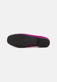 Flache Schuhe mit einem lebhaften pinken Wildleder-Obermaterial und einer strukturierten schwarzen Gummisohle. Sie verfügen über ein niedriges Profil und dezente Steppdetails.