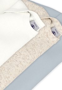 Τρία διπλωμένα μακρυμάνικα πουκάμισα: ένα λευκό, ένα ανοιχτό μπεζ με πουά σχέδιο και ένα ανοιχτό γαλάζιο. Το κάθε ένα έχει στρογγυλή λαιμόκοψη και υφή υφάσματος.