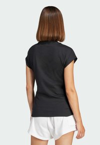 Black short-sleeve t-shirt with a high neckline and fitted design, made of soft fabric, worn with white shorts, displaying a simple, clean look.