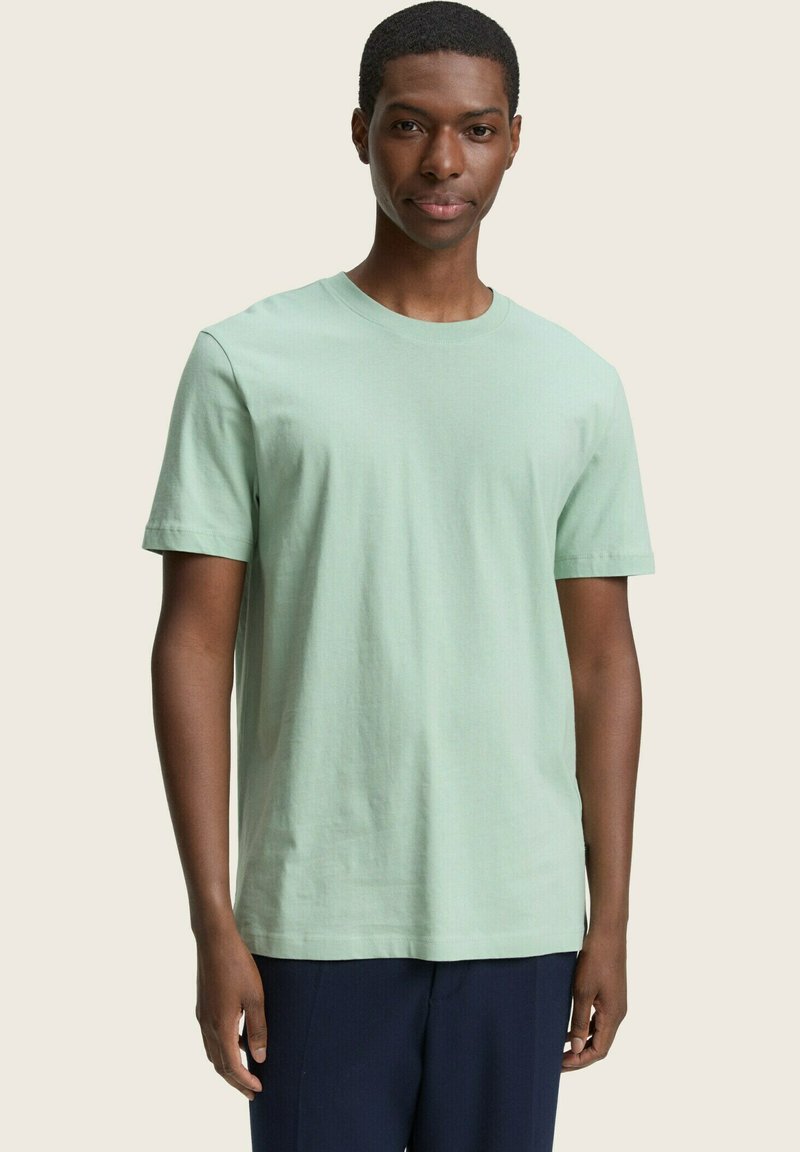 T-shirt in cotone verde menta chiaro con maniche corte e scollatura rotonda, caratterizzato da una texture morbida e una vestibilità comoda.