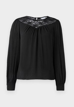 Sort langærmet bluse med en blonde yoke, sammensyning ved halsudskæringen og elastiske manchetter med broderede detaljer. Blødt stof.